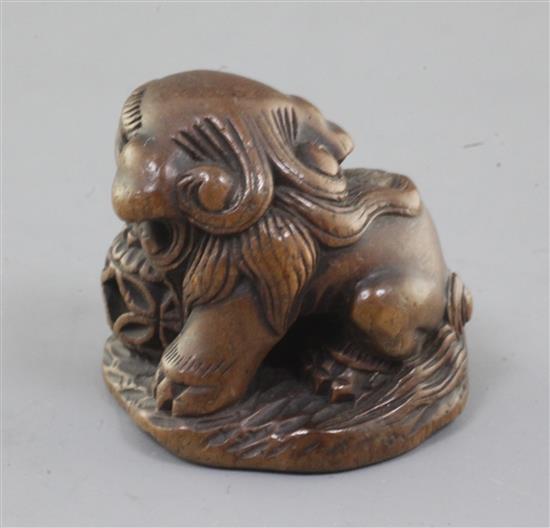 A Japanese wood netsuke of a shishi, seated on a rock, 19th century, w. 3.6cm